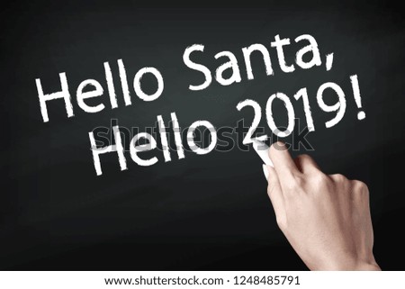 Hand holding a chalk and writing hello santa and hello 2019. Wishing you wonderful memories during this joyous season.