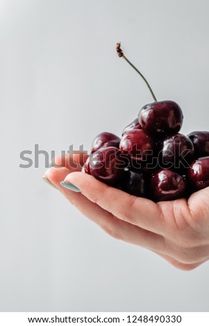  Female hand holds a handful of berries on white kitchen napkin. White background Red Fresh healthy food concept
