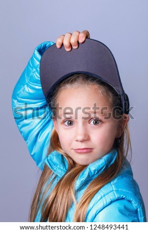 Portrait of a teenage girl removing a baseball cap from her head