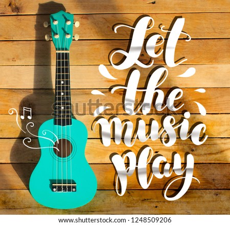 Guitar photo and handwritten digital text "Let the music play". Music stamp, poster. Wooden background, solar lighting, long shadows, bright contrasting picture