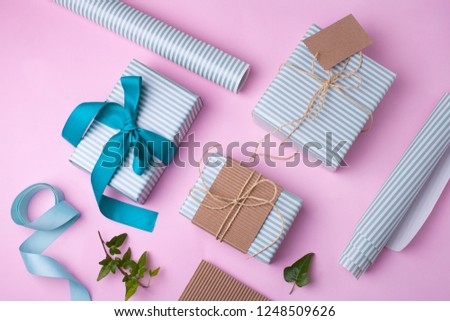 Striped gifts and blue striped paper on a pink background. View from above