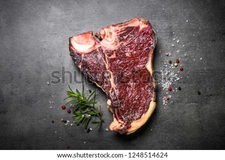 Dry aged beef steak t-bone on black slate background. Top view. Royalty-Free Stock Photo #1248514624