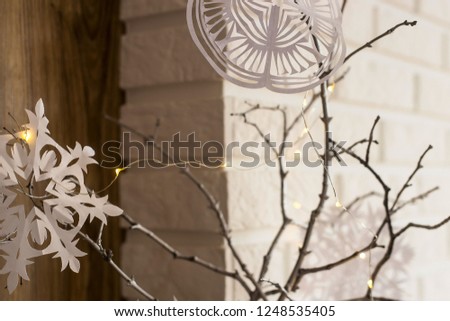 Self-made paper snowflakes are fixed on sticks of a tree as a winter Christmas decoration of an apartment. Minimalism