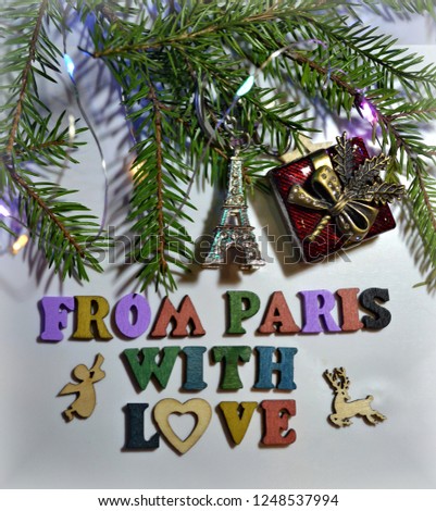 Christmas and New-Year's greeting card with Christmas tree branches, the Eiffel Tower, gift and FROM PARIS WITH LOVE text. Paris vacations. Winter holidays. Christmas background. Top view.