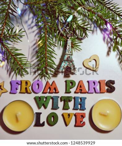 Christmas and New-Year's greeting card with Christmas tree branches, the Eiffel Tower, candles and FROM PARIS WITH LOVE text. Paris vacations. Winter holidays. Christmas background. Top view.