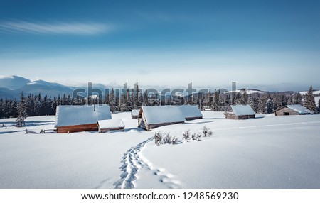 Wonderful Winter landscape at mountain highland during sunrise. Awesome alpine valley with snowcovered wooden huts . amasing wintry scenery. 