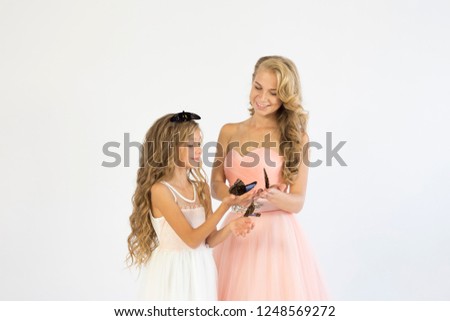 Beautiful mother with her daughter in elegant dresses with live butterflies in the studio