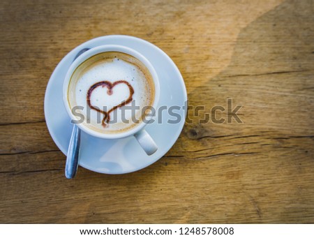 Cup of coffee with a heart on a wooden light brown table with copy space. valentine day with love, concept.