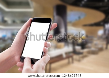 Smartphone blank screen in woman hands over blurred background at Holel.
