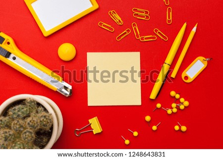Flat lay, top view office table desk. Workspace with blank adhesive notes,  office supplies on red background.