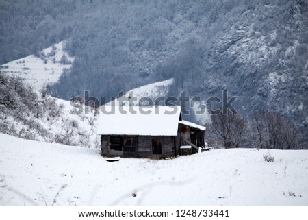 Winter landscape with small cottage in snowy mountains