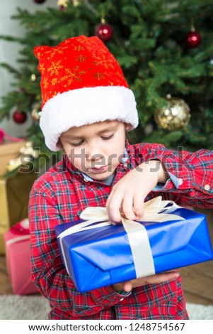 Christmas child time. Child boy in santa hat with Christrmas present box.