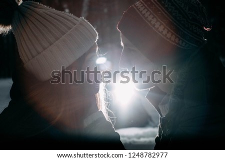 Loving couple in winter clothes on nature in the snow. Back light on the silhouettes of lovers.