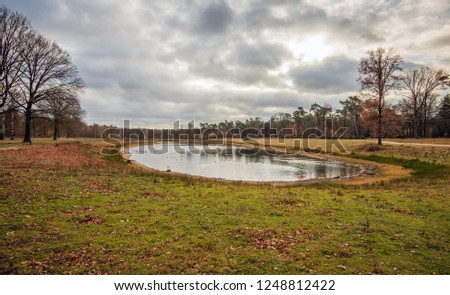 Small partially dried up lake in the autumn season. The natural pond, in the Dutch province of Noord-Brabant, was originally a clay quarry from which raw material for the brick factory was extracted.