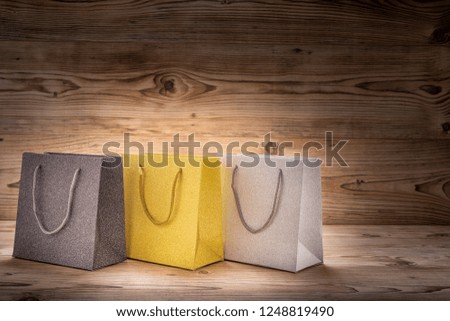 Three colorful shopping bags in front of a wood background