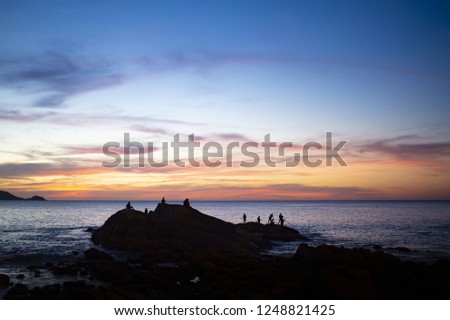 Silhouette of some people enjoying the beautiful sunset on a coast in Phuket, Thailand.