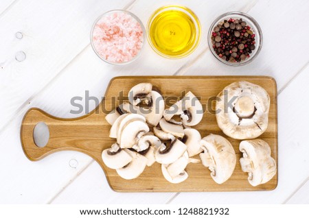 White fresh sliced champignons in pan on kitchen table. The concept of cooking mushroom dishe. Studio Photo