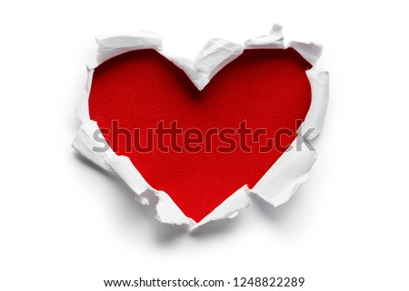 Heart shaped red hole torn through paper, isolated on white background