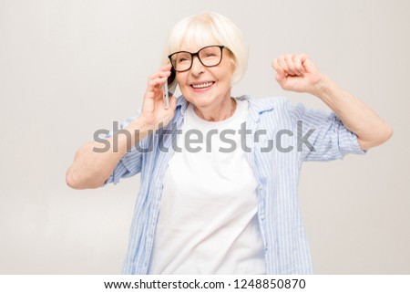 Phone conversation. Positive happy aged woman smiling while talking on the phone, isolated over white background. 