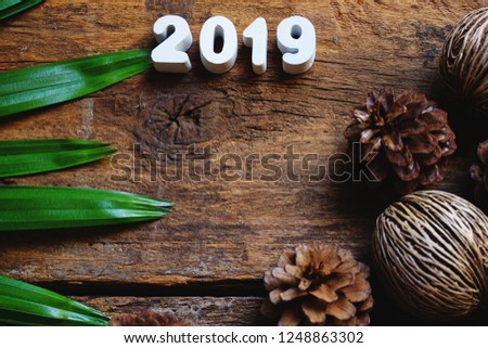 Old wooden texture background decorated to be picture frame with green leaf and pine seed in classic color tone, copy space, happy new year 2019 concept