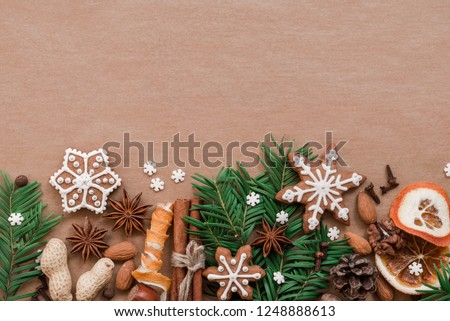 Christmas decoration with spices and cookies in the shape of snowflakes, cinnamon sticks and star anise on dark brown paper background. Top view.