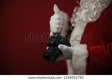 Santa Claus using DSLR camera taking images showing thumb up. Happy Christmas Evening and New Year celebration background. Fun loving creative costume time