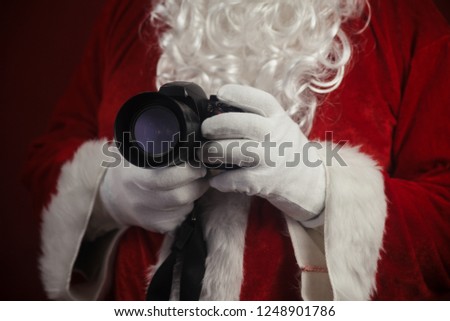 Santa Claus using holding in hands DSLR camera. Christmas and New Year celebration background