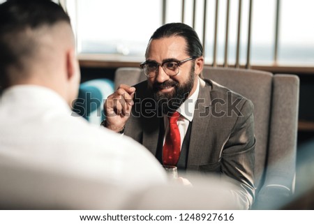 Feeling cheerful. Bearded man feeling cheerful and joyful while communicating with business partner