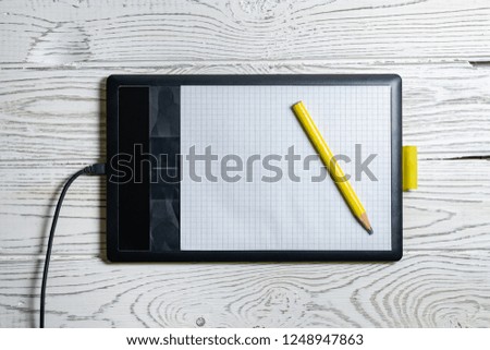Graphic tablet with pen for illustrators and designers, on white wooden background