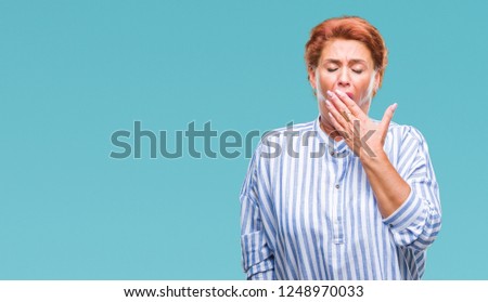 Atrractive senior caucasian redhead woman over isolated background bored yawning tired covering mouth with hand. Restless and sleepiness.