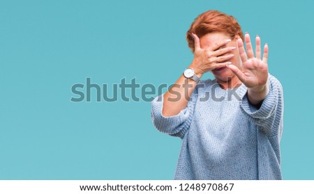 Atrractive senior caucasian redhead woman wearing winter sweater over isolated background covering eyes with hands and doing stop gesture with sad and fear expression. Embarrassed and negative concept