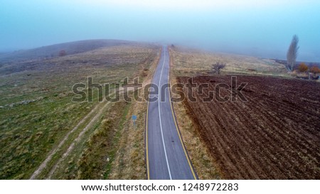 Aerial view on  speed road, partly covered by fog. Vertical view on rural countryside in autumn, foggy morning. Misty road.