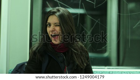Flirtatious girl blinks to camera riding the metro subway looking directly to camera.jpeg