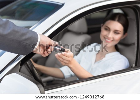 Rental contract. Man auto dealer offering car key to woman