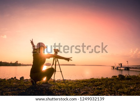 silhouette of young woman photographer,  of landscape at sunset.