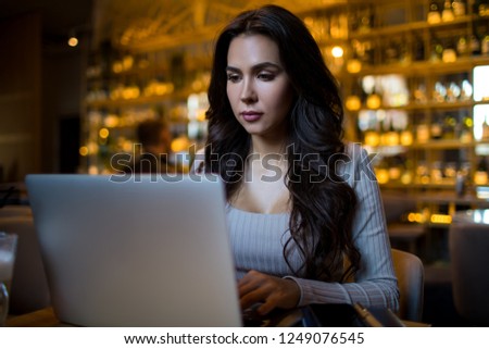 Serious woman professional business worker searching information in internet via modern laptop computer while sitting in restaurant interior. Confident female CEO checking e-mail via netbook device 