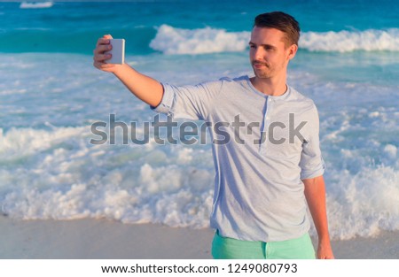 Young man taking selfie on the beach background the ocean on caribbean island