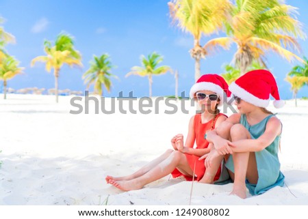 Little adorable girls in Santa hats during beach Christmas vacation
