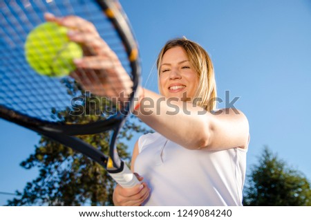 Cute female tennis player holding ball on racket worm eye view 