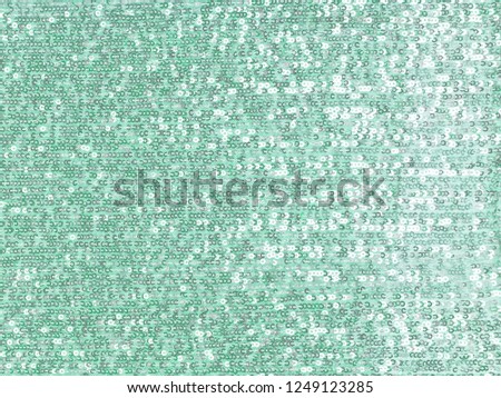 Background sequin, glitter surfactant. Holiday abstract glitter background with blinking lights. Fabric sequins in bright colors. Fashion fabric glitter, sequins. Turquoise
