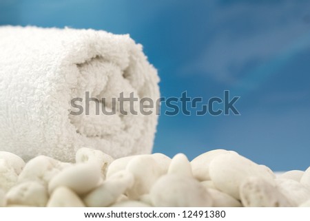 White towel and white stones on bluse sky background