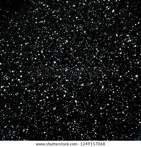Snowfall on a black background. Snowstorm texture. Shot of flying snowflakes in the air. Design element.  White spots on a black backdrop. Free space for text.