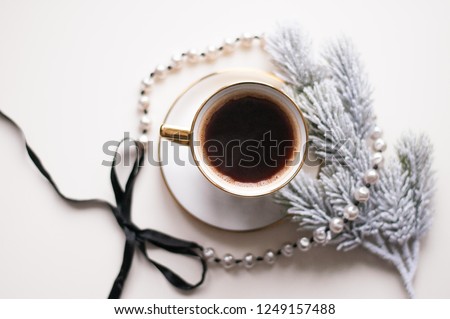 Coffee in a golden cup on a white background.
Good New Year spirit. Coffee in the winter for the new year.
Saucer and cup with a drink. Beautiful card with coffee.