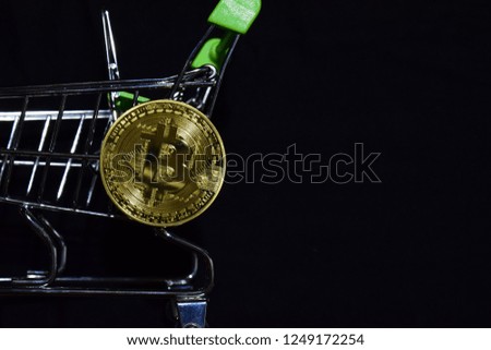 Bitcoin gold and shopping cart on black background. Bitcoin outside a shopping cart. Business concept