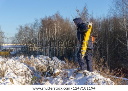 Surveyor comes with a tripod and gauge in winter at a construction site