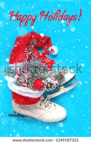Christmas skates ice with festive decor. Christmas toys, pine branch, candy and cones in the bouquet. Flat top view.on blue background  with snow in and inscription Happy Hollidays