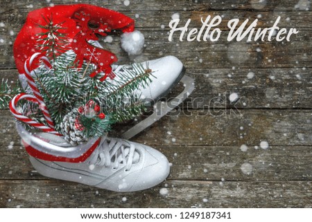Christmas skates ice with festive decor. Christmas toys, pine branch, candy and cones in the bouquet. Flat top view.on wooden background with snow and the words hello winter