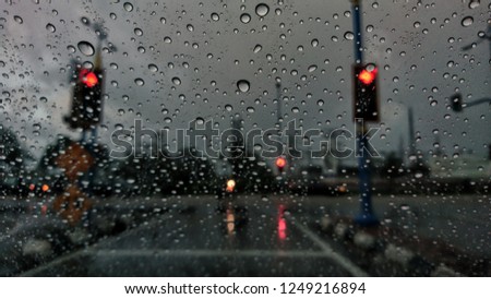Selective focus of rain drop on glass and cars on the road during the day. 
