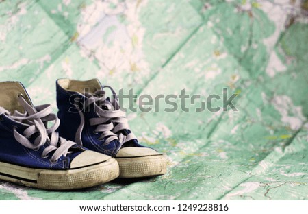 Blue sneakers on the background of a physical map. Travel.