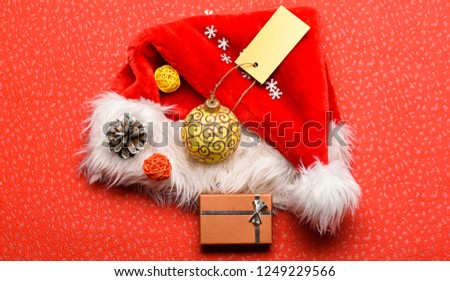 Keep family traditions. Christmas presents from santa. Attributes of winter holidays. New year and christmas decorations. Santa hat red background top view. Santa hat with christmas gift box.